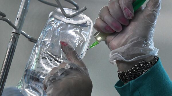 Медицинский сотрудник вводит лекарство в капельницу во время операции в госпитале
