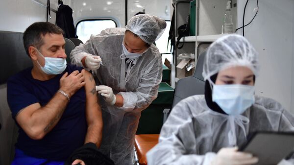 Медик делает прививку с вакциной против гриппа в мобильном пункте вакцинации возле станции метро Курская в Москве