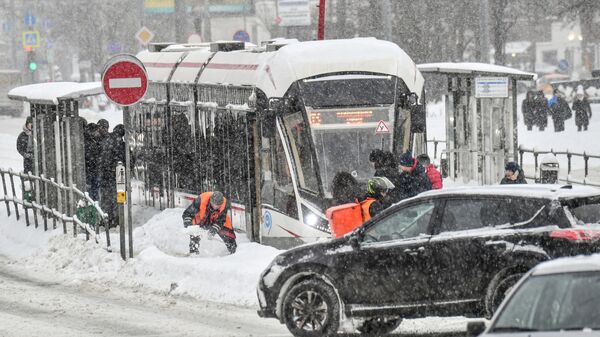 Работник коммунальной службы очищает от снега остановку московского городского транспорта