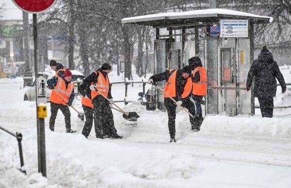 Работники коммунальной службы чистят от снега остановку московского городского транспорта
