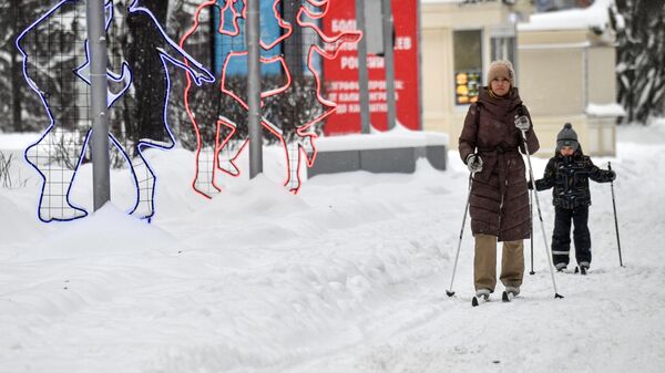 Женщина с ребенком катаются на лыжах в парке Сокольники