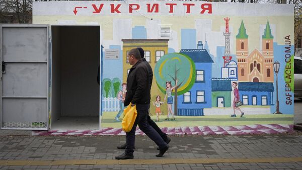 Люди проходят мимо бетонного навеса с надписью укрытие, установленного на остановке в украинском городе