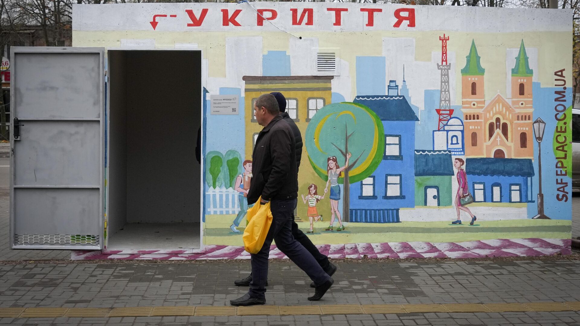 Люди проходят мимо бетонного навеса с надписью укрытие, установленного на остановке общественного транспорта в Николаеве - РИА Новости, 1920, 17.02.2023