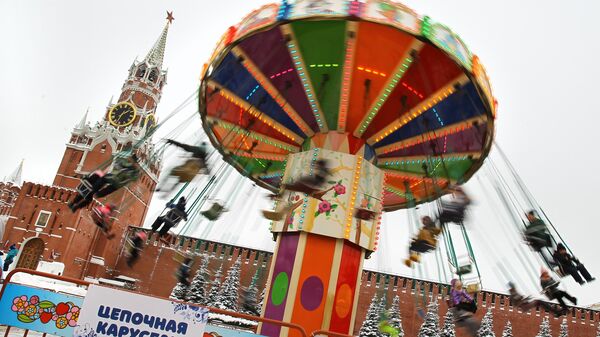 Посетители предновогодней ГУМ-Ярмарки катаются на карусели на Красной площади. Новый год в Москве