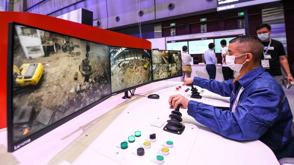 Рабочий в Шанхае использует систему дистанционного управления, поддерживаемую технологией 5G, для управления краном, расположенным в провинции Хунань