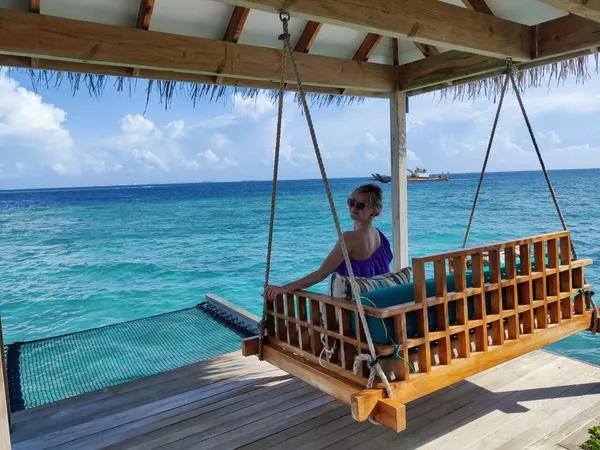 Мальдивы. Туристка на качелях на вилле в отеле Hilton Maldives Amingiri Resert & Spa