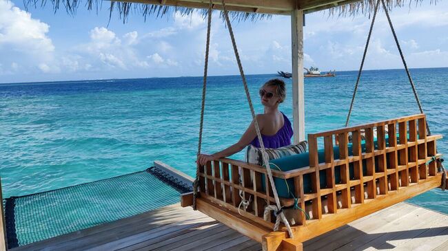 Мальдивы. Туристка на качелях на вилле в отеле Hilton Maldives Amingiri Resert & Spa