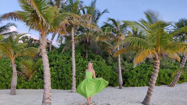 Туристка на пляже под пальмами на Мальдивах