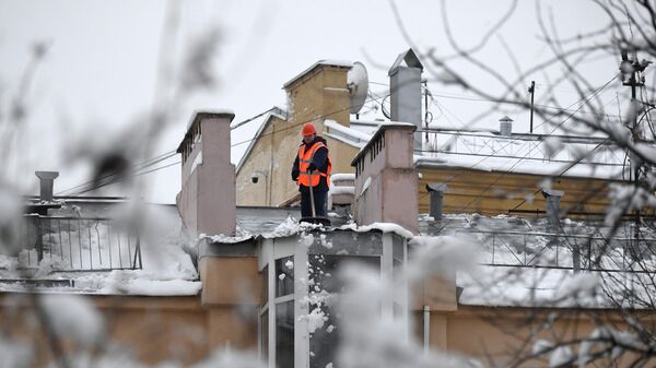 Сотрудник коммунальной службы во время уборки снега с крыши дома в Москве