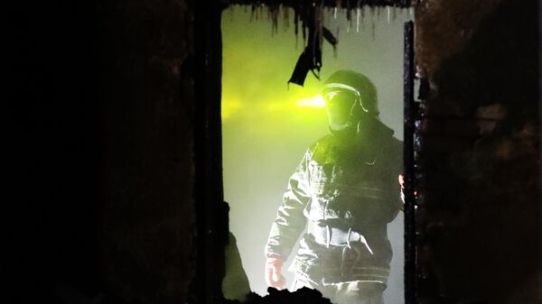Сотрудник пожарной службы МЧС РФ работают на месте пожара 