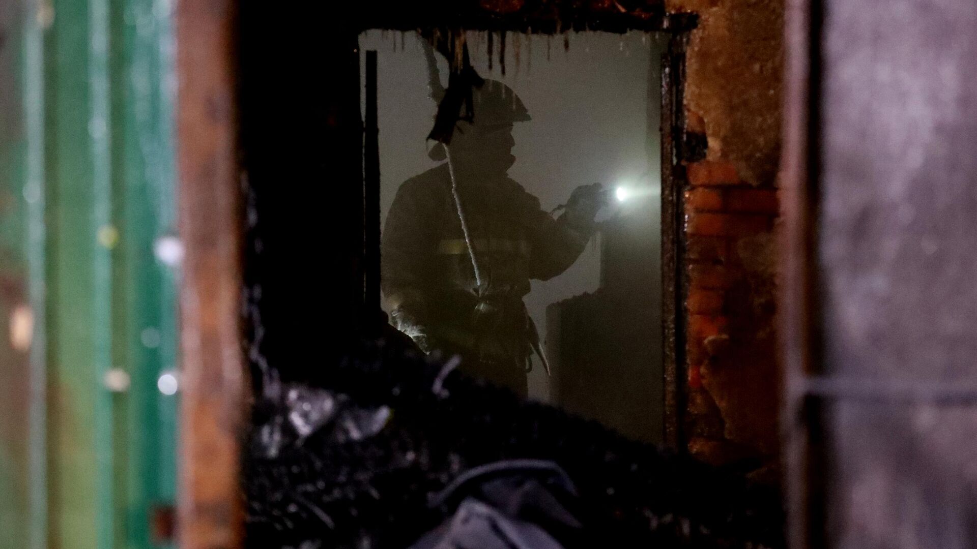 Сотрудник пожарной службы МЧС РФ работает на месте пожара в здании частного дома престарелых в Кемерово - РИА Новости, 1920, 26.12.2022