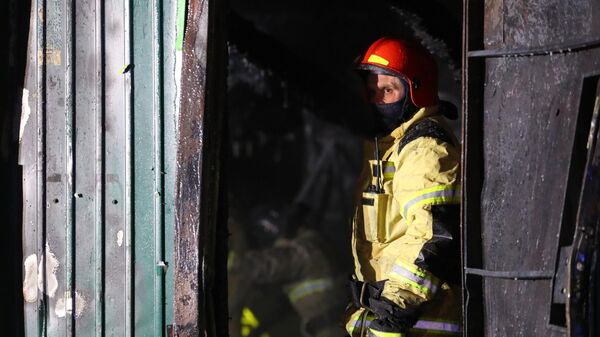 Сотрудник пожарной службы  МЧС РФ работает на месте пожара в здании частного дома престарелых на улице Таврическая в Кемерово