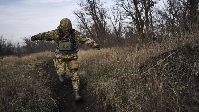 Украинский солдат бежит в укрытие на линии соприкосновения возле Марьинки