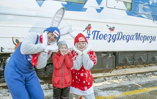 Аниматоры из команды  Деда Мороза с ребенком у поезда Деда Мороза на железнодорожном вокзале в Перми