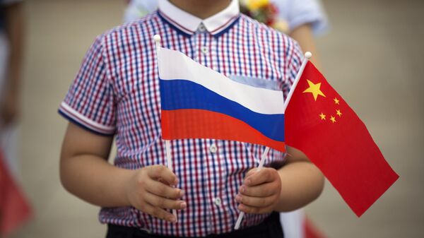 Мальчик держит российский и китайский флаги