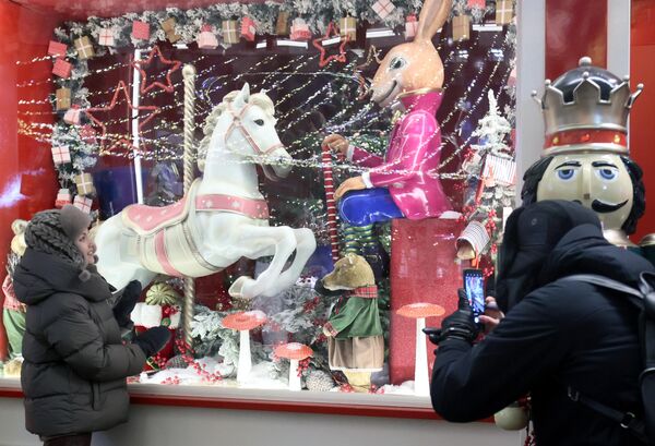 Девушка фотографируется у витрины с игрушками на фестивале Путешествие в Рождество на Манежной площади в Москве