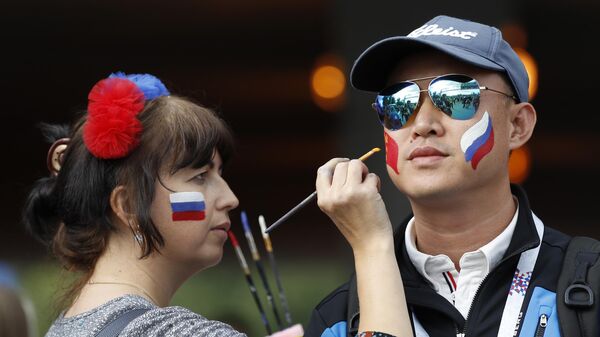 Девушка рисует флаг Китая на щеке молодого человека 