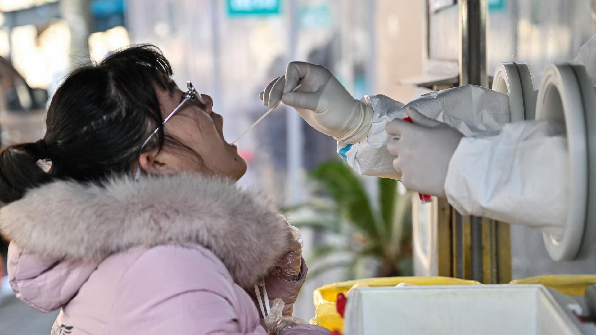 Медицинский работник берет образец мазка у женщины для тестирования на коронавирус Covid-19 в районе Цзинъань в Шанхае - РИА Новости, 1920, 29.12.2022