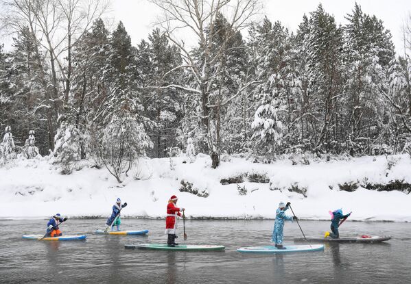 Спортсмены группы сапсерфинга SUP-Novosibirsk участвуют в новогоднем заплыве по незамерзающей реке недалеко от Новосибирска