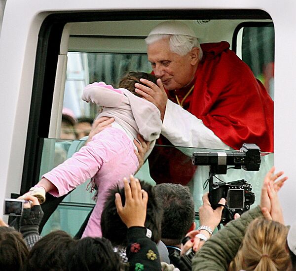 Папа Римский Бенедикт XVI целует ребенка во время празднования Всемирного дня молодежи в Сиднее