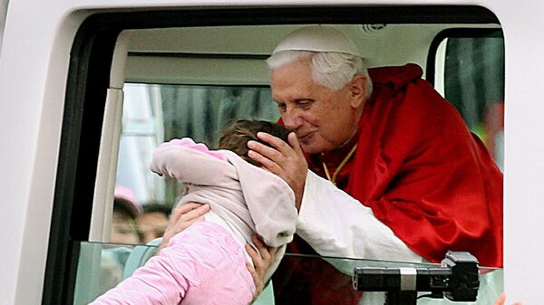 Папа Римский Бенедикт XVI целует ребенка во время празднования Всемирного дня молодежи в Сиднее