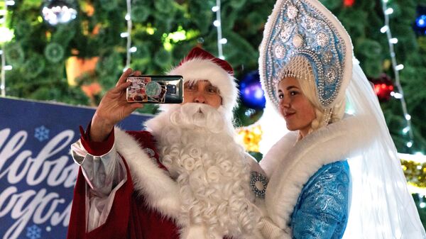 Дед Мороз и Снегурочка фотографируются во время встречи Нового года в центре города Петропавловска-Камчатского