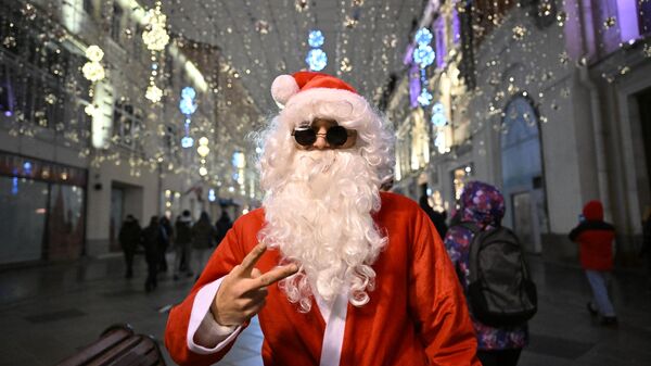 Мужчина в костюме Санта-Клауса во время встречи Нового года на Никольской улице в Москве