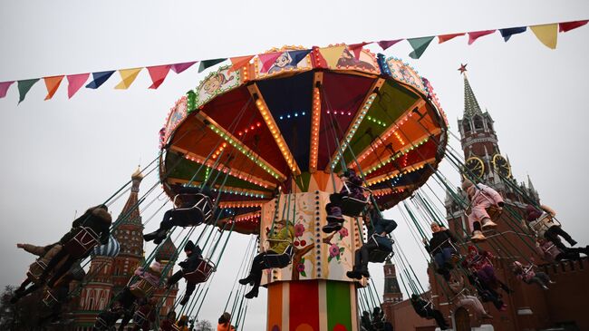 Люди катаются на карусели на Красной площади в Москве