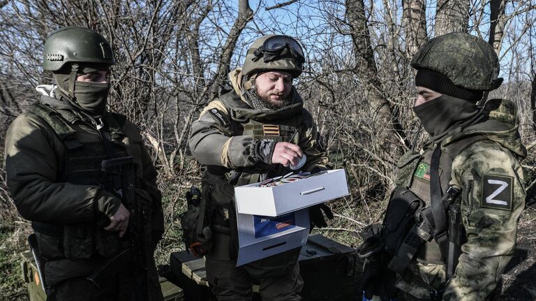 Военный корреспондент медиагруппы Россия сегодня Ростислав Журавлев (в центре) раздает присланные шевроны бойцам на передовой, участвующим в боевых действиях на Запорожском направлении