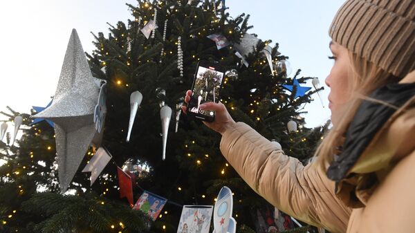 Девушка на выставке новогодних дизайнерских елей, выставленных в рамках зимнего фестиваля Путешествие в Рождество на площади у ЦУМа в Москве