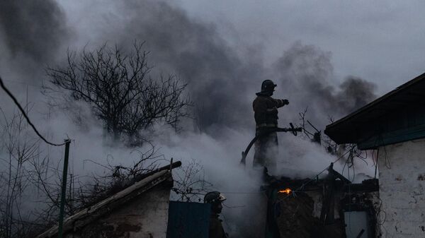 Пожарные тушат огонь в доме, куда попал снаряд при обстреле Донецка со стороны ВСУ