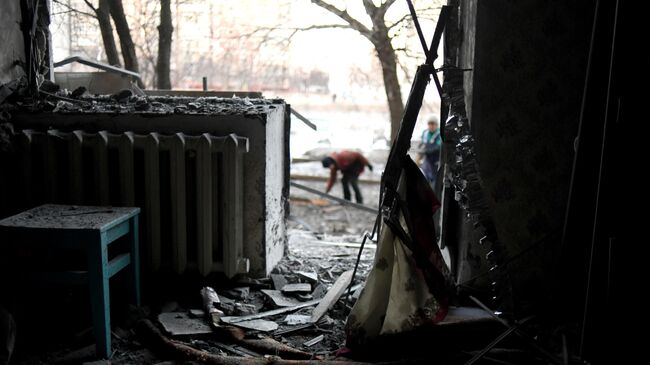 Местные жительницы убираются у дома, пострадавшего в результате ночного обстрела в Горловке.