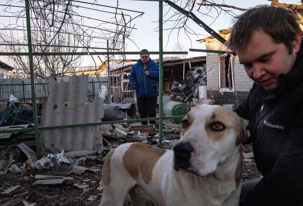 Мужчины с собакой во дворе дома, пострадавшего в результате обстрела в Петровском районе Донецка