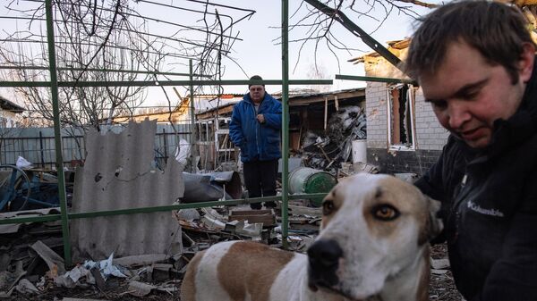 Мужчины с собакой во дворе дома, пострадавшего в результате обстрела Донецка