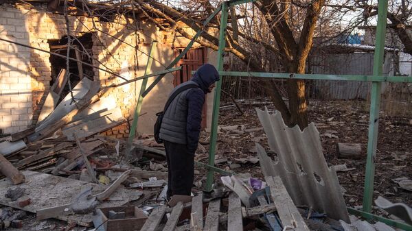Мужчина во дворе дома, пострадавшего в результате обстрела в Петровском районе Донецка