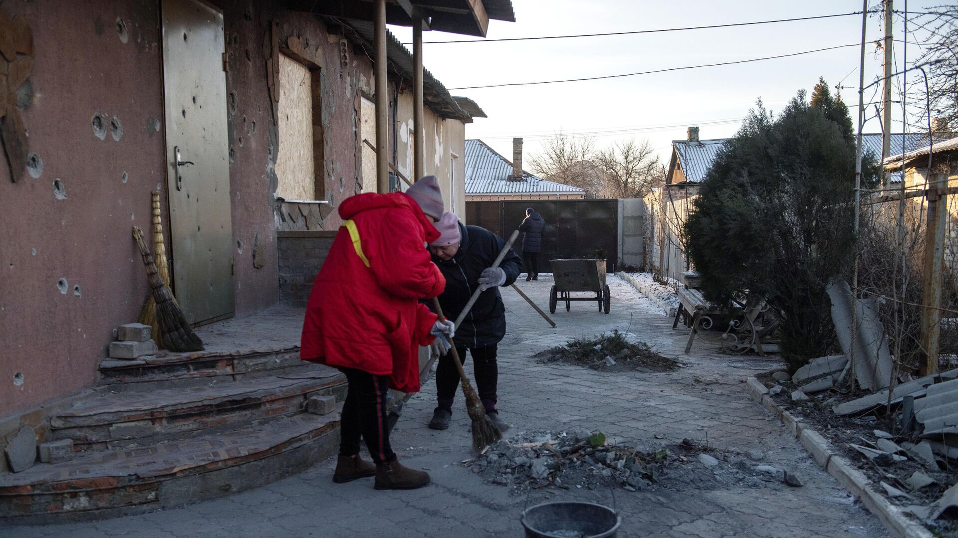 Местные жительницы убираются во дворе дома, пострадавшего в результате обстрела в Петровском районе Донецка - РИА Новости, 1920, 27.02.2023