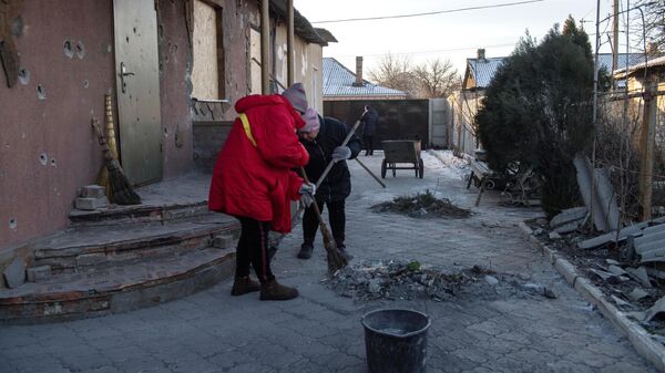 Жительницы Донецка убираются во дворе дома, пострадавшего в результате обстрела