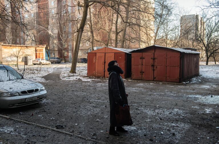 Женщина во дворе дома, пострадавшего в результате обстрела в Петровском районе Донецка