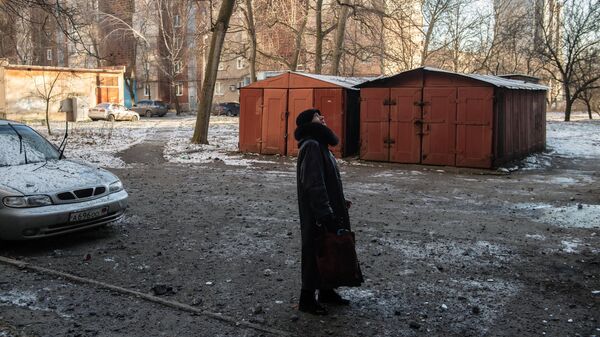 Женщина во дворе дома, пострадавшего в результате обстрела в Петровском районе Донецка