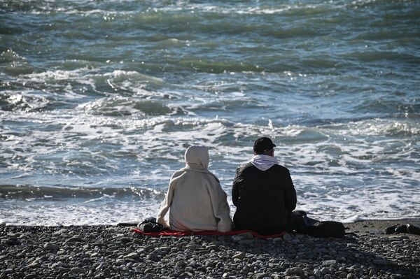 Отдыхающие сидят на галечном пляже у Черного моря в Сочи