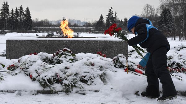 Мальчик возлагает цветы к вечному огню у монумента Мать-Родина на Пискаревском мемориальном кладбище в память о погибших в годы блокады