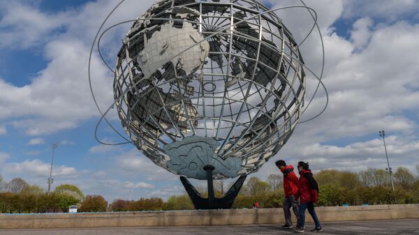 Пара проходит мимо скульптуры Unisphere в Нью-Йорке, США
