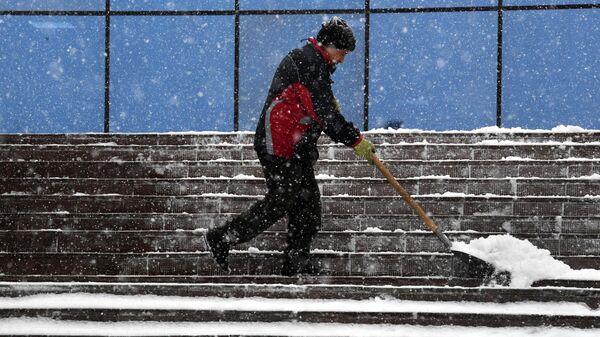 Сотрудник коммунальных служб убирает снег