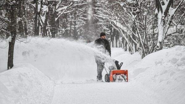 Мужчина чистит дорожки от снега