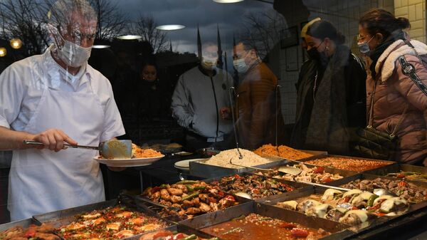 Сотрудник одного из кафе Стамбула накладывает еду в тарелку для посетителей
