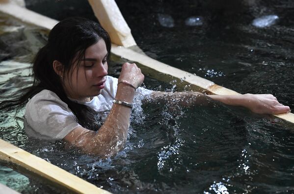 Девушка окунается в иордань во время празднования Крещения на набережной Спортивной гавани во Владивостоке