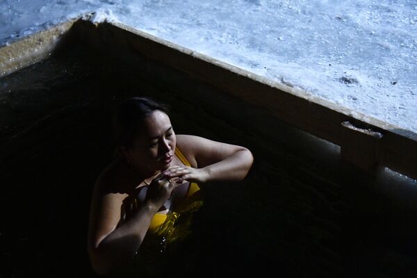 Девушка окунается в купель во время празднования Крещения на озере Шарташ в Екатеринбурге