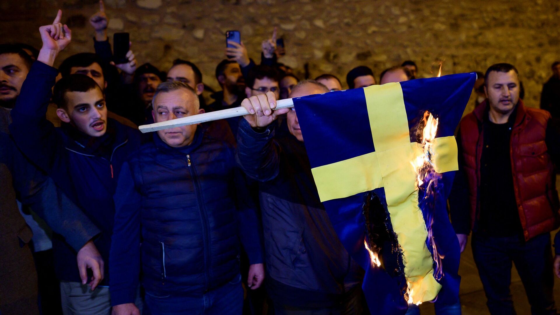 Протестующие сжигают флаг Швеции во время демонстрации перед генеральным консульством страны в Стамбуле - РИА Новости, 1920, 22.01.2023