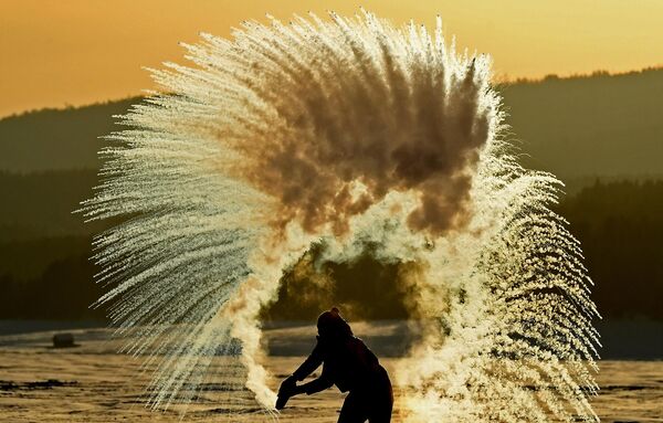 Девушка устраивает ледяной фейерверк, выплескивая горячую воду в воздух в Красноярском крае