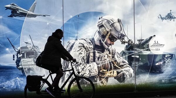 Мужчина на велосипеде проезжает мимо рекламного баннера возле штаб-квартиры крупнейшего немецкого производителя оружия Rheinmetall AG в Дюссельдорфе, Германия